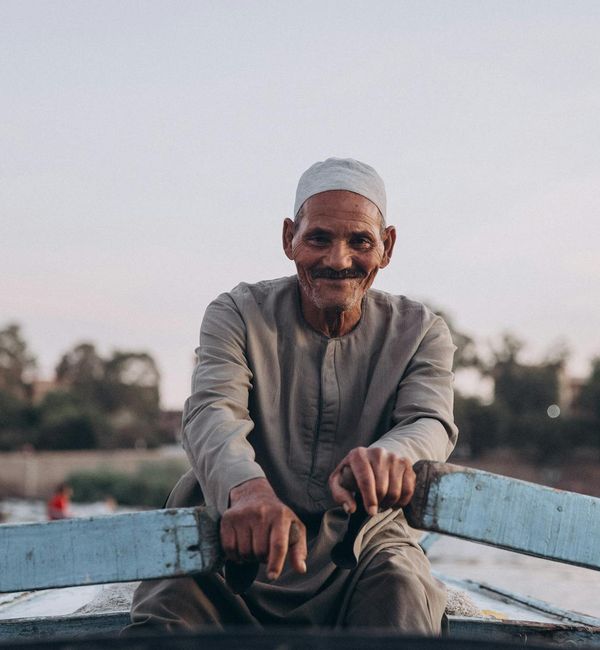 Smiling man stretching outdoors with a serene natural background.